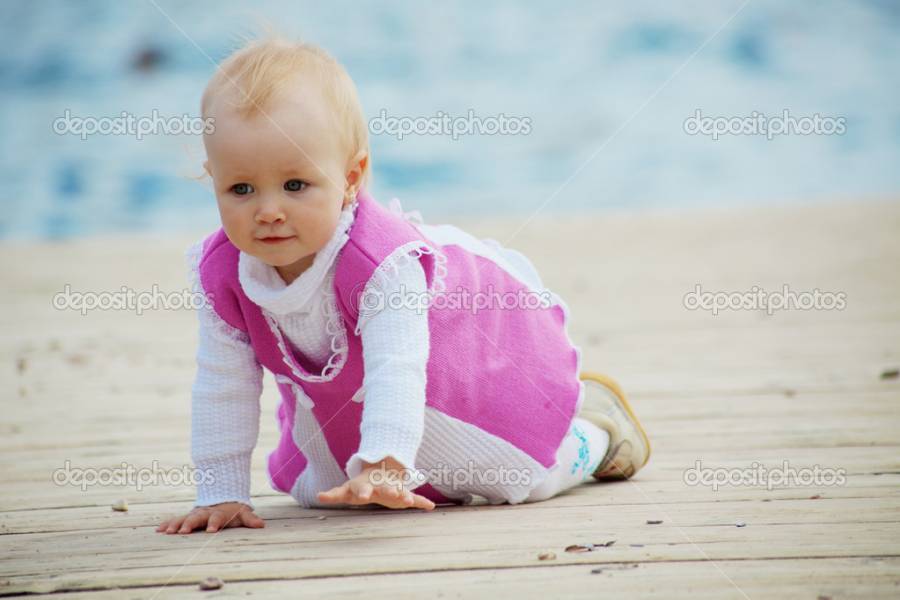 Portrait of little cute baby girl creeping on berth near sea
